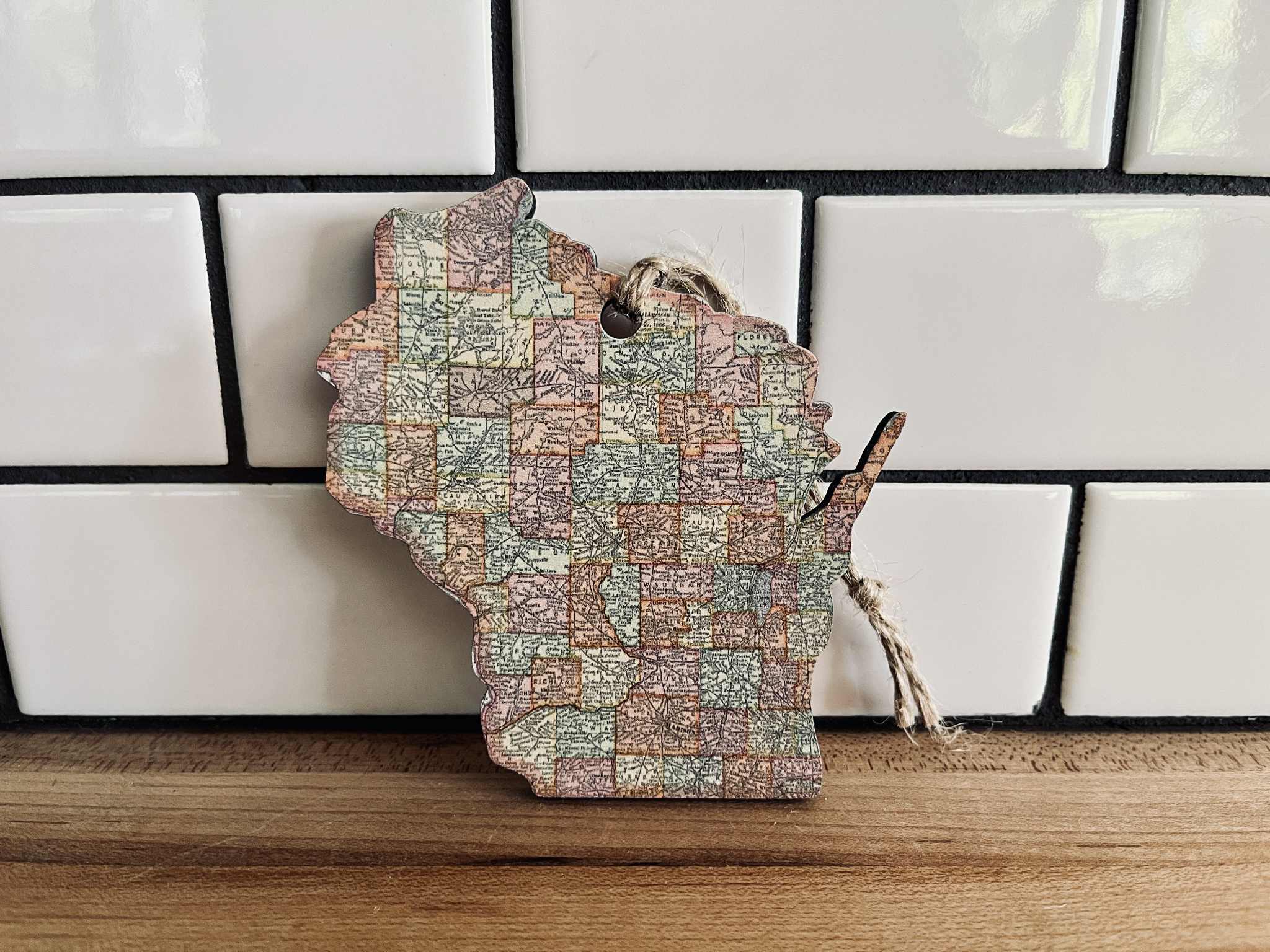 Map-shaped wooden cutting board with vintage map design on a tiled wall background