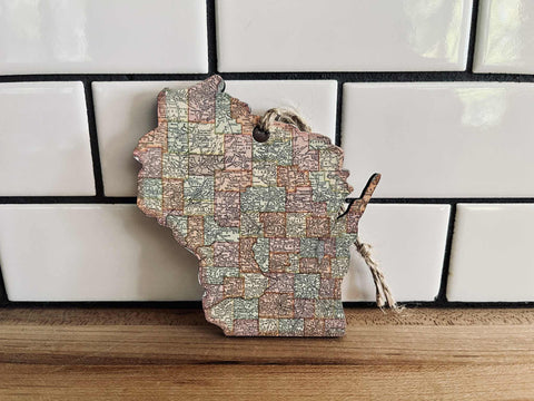 Map-shaped wooden cutting board with vintage map design on a tiled wall background