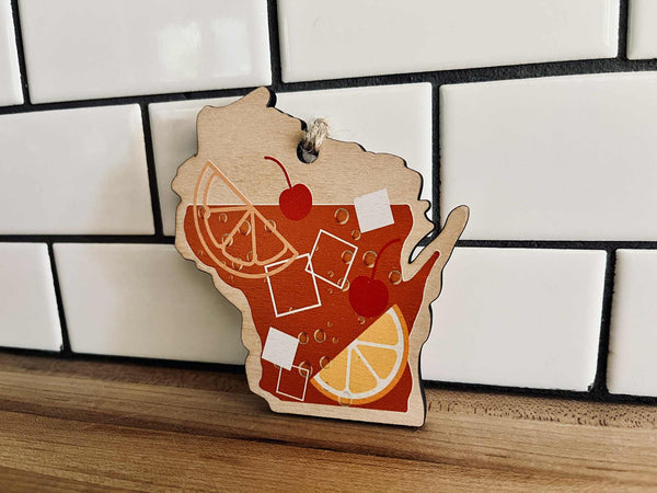 Wooden ornament shaped like Wisconsin with a cocktail design on a tiled wall background
