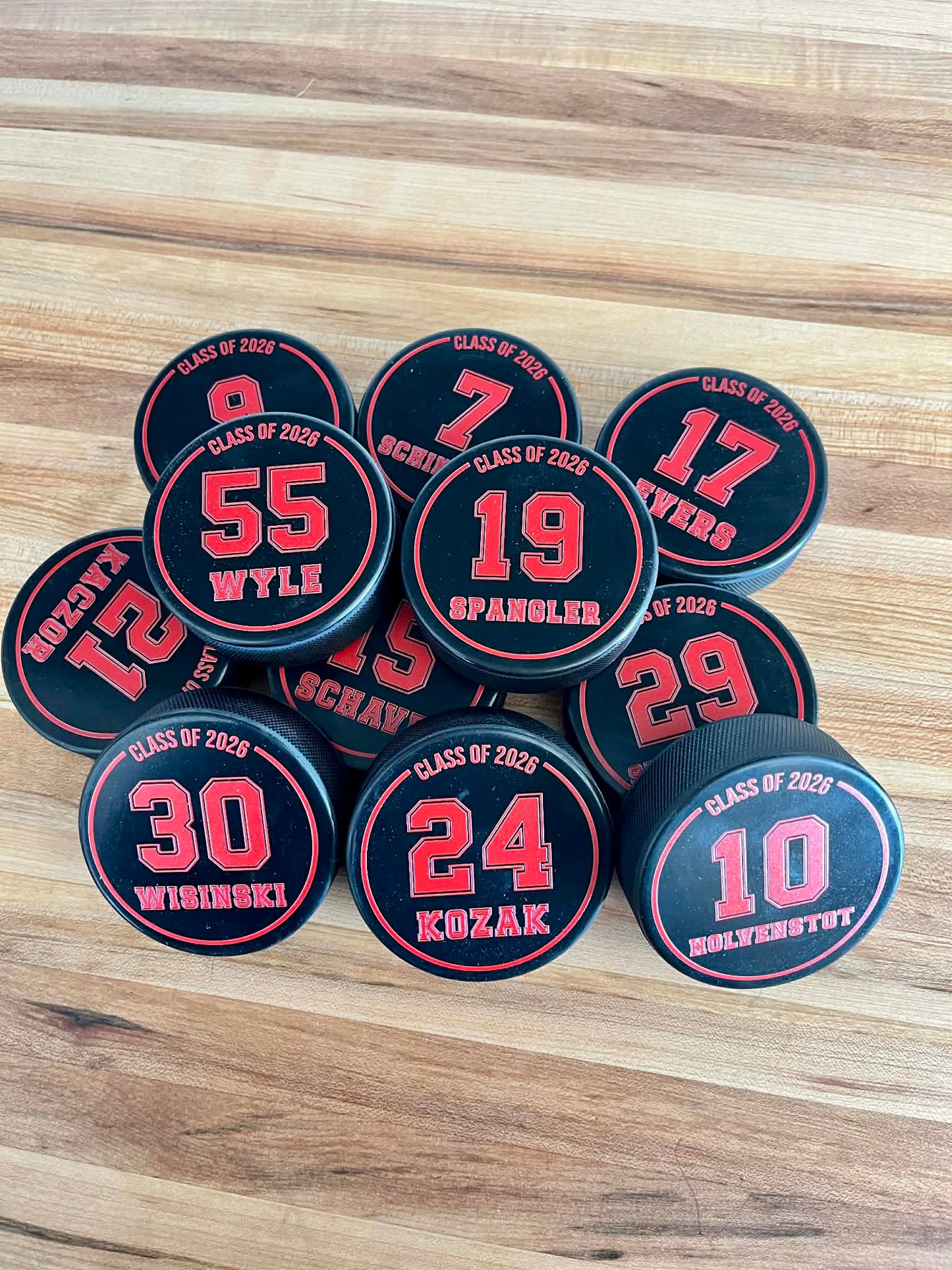 A collection of custom hockey team pucks for end-of-season awards and senior night celebrations.