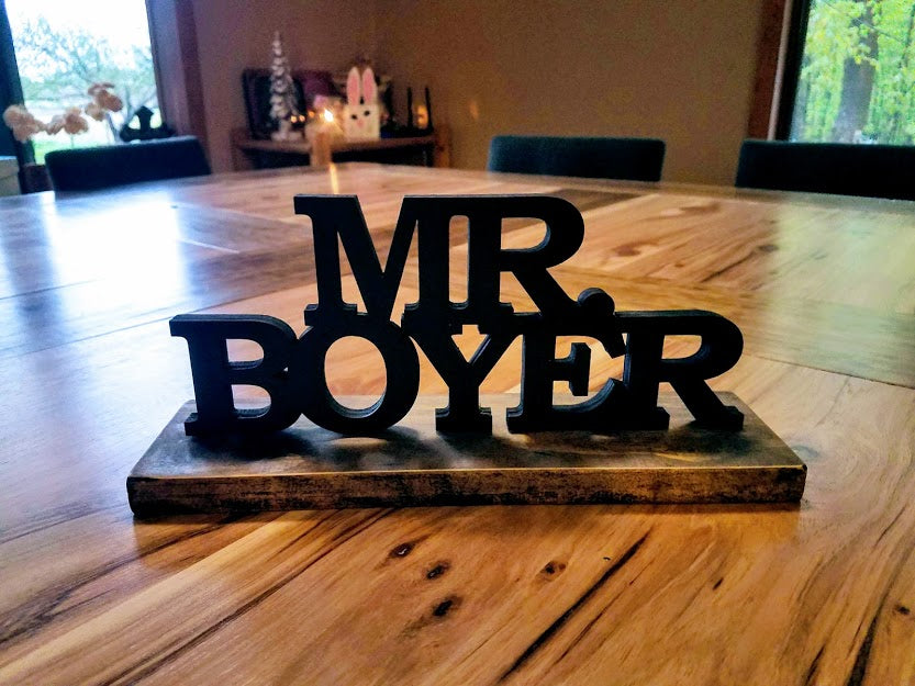 Hand-painted 3D wood desk name plate with raised black lettering for a teacher's desk.