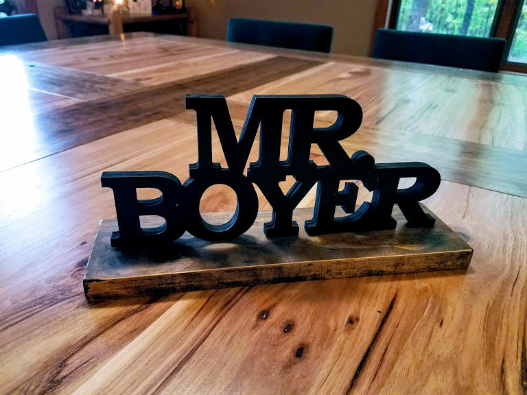 Hand-painted 3D wood desk name plate with raised black lettering for a teacher's desk.