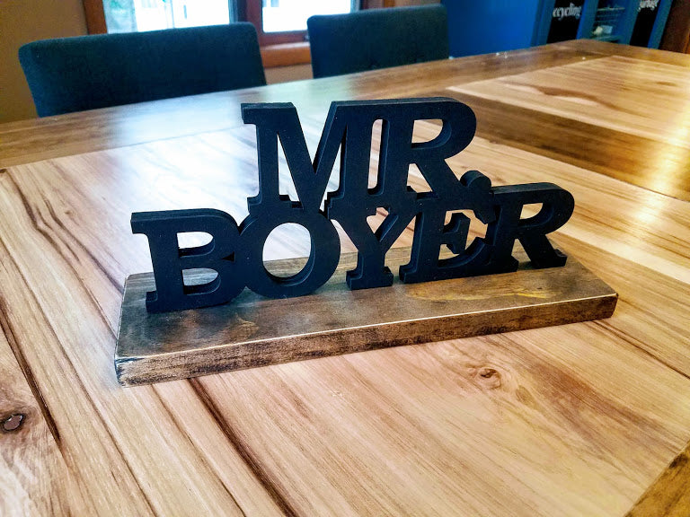 Hand-painted 3D wood desk name plate with raised black lettering for a teacher's desk.